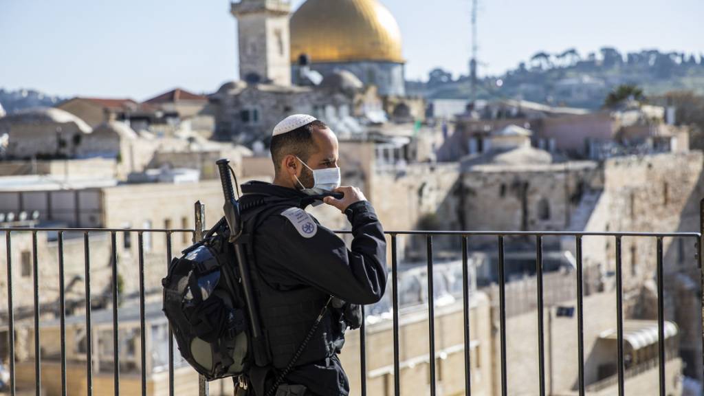 ARCHIV - Ein israelischer Polizist mit Mundschutz steht in der Altstadt von Jerusalem Wache. Im Hintergrund der Felsendom auf dem Tempelberg. Foto: Ilia Yefimovich/dpa