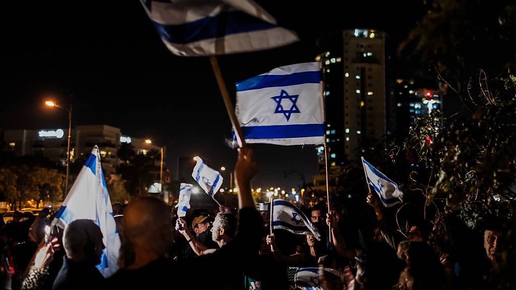 Menschen jubeln mit israelischen Fahnen, nachdem ein Hubschrauber mit von Hamas-Kämpfern frei gelassenen Geiseln im Schneider Children's Medical Center of Israel gelandet ist. Foto: Ilia Yefimovich/dpa