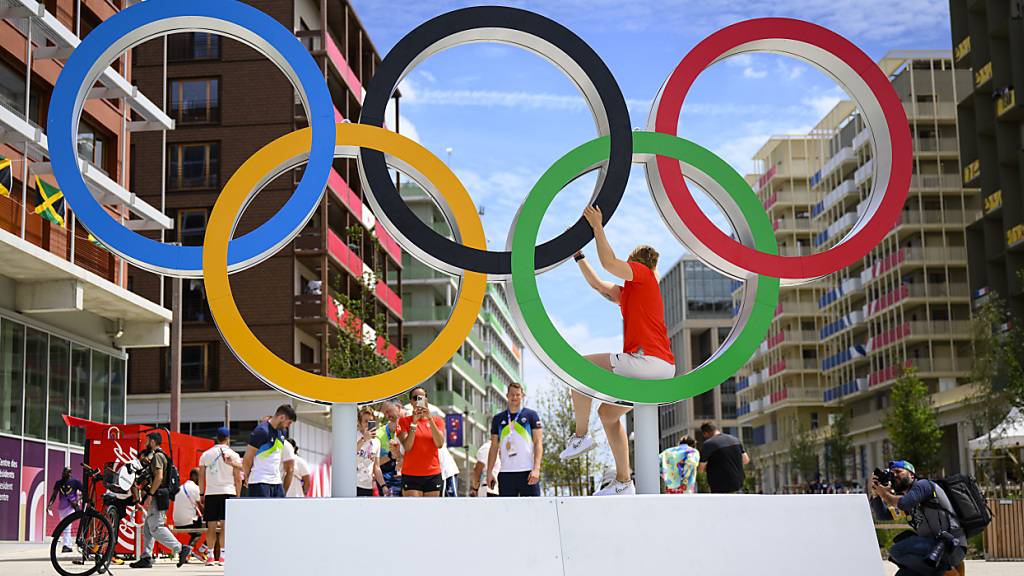 Athleten posieren mit den Olympischen Ringen während einer Medientour durch das Olympische Dorf