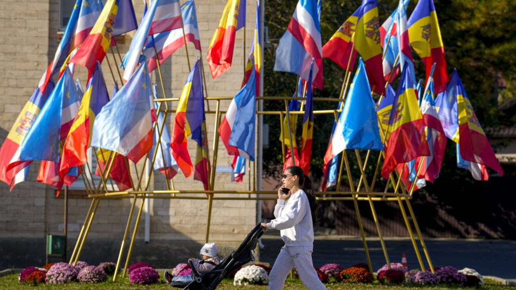 ARCHIV - Eine Frau schiebt einen Kinderwagen vor moldauischen und gagausischen Flaggen in Comrat, der Hauptstadt von Gagausien. Foto: Vadim Ghirda/AP/dpa