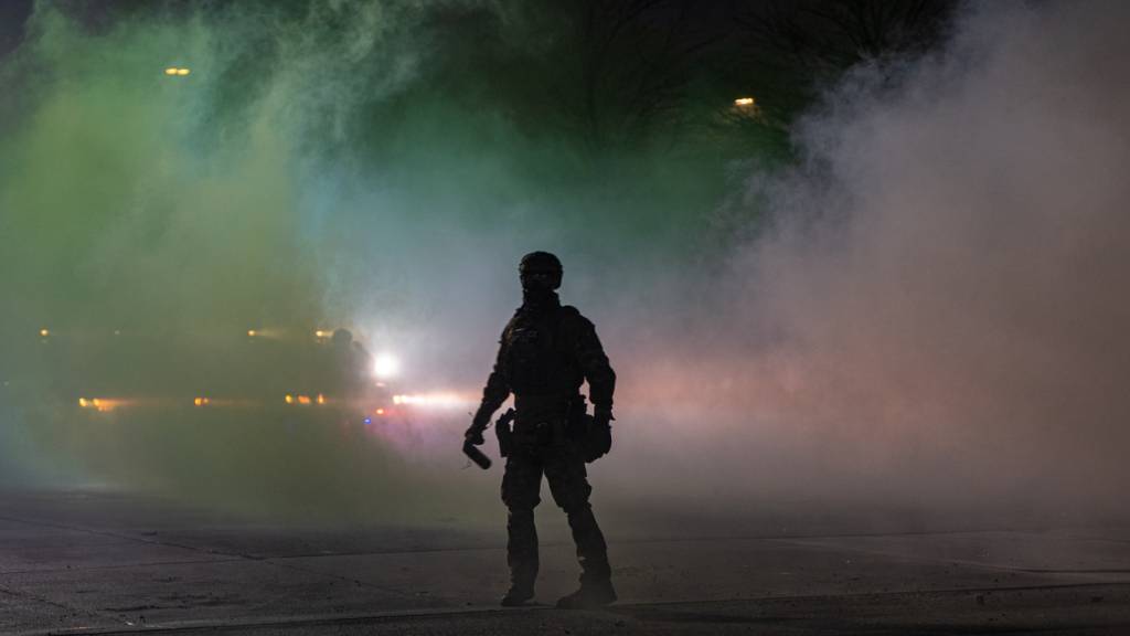 Ein Bundesbeamte der Einwanderungsbehörde ICE ist vor dem Bishop Whipple Federal Building zu sehen, nachdem Tränengas eingesetzt wurde. Nach den tödlichen Schüssen auf eine Frau in Minneapolis halten die Proteste gegen die Behörde an. Foto: Jen Golbeck/AP/dpa