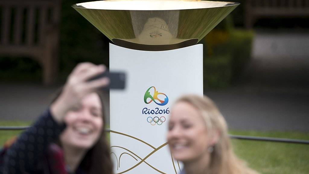 Zwei junge Frauen machen ein Selfie vor der Olympischen Flamme, die am Wochenende vor dem Olympischen Museum in Lausanne zu sehen ist. Am Montag wird die Flamme zur langen Reise in die brasilianische Hauptstadt Brasilia starten.