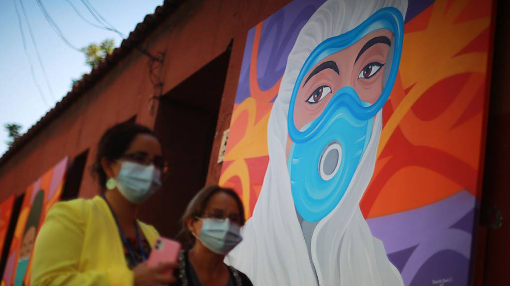 Zwei Frauen mit Masken gehen an einem Wandgemälde zur Anerkennung der Mitarbeiter des Gesundheitswesens bei der Bekämpfung des Covid-19 vorbei. (Archivbild)