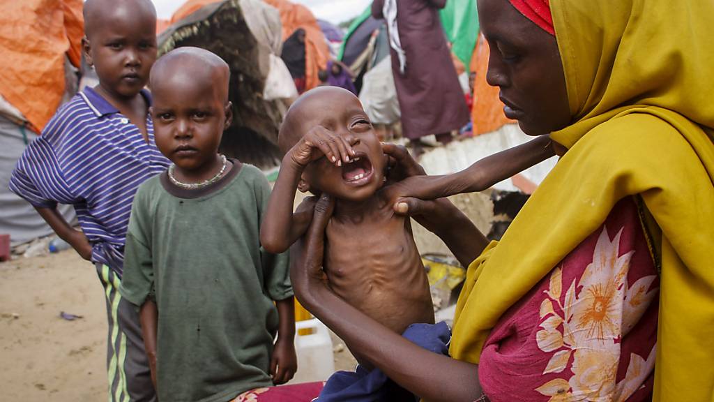 ARCHIV - Maryan Madey (r), die aus der von Dürre heimgesuchten Region Lower Shabelle in Somalia geflohen ist, hält ihre unterernährte Tochter Deka Ali in einem Lager für Vertriebene. Foto: Farah Abdi Warsameh/AP/dpa
