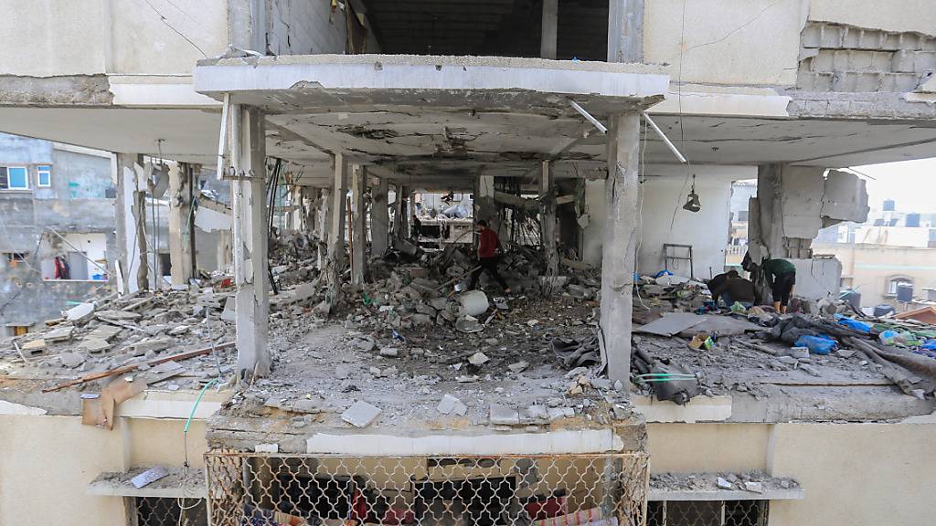 Palästinenser begutachten die Schäden und Trümmer der zerstörten Häuser nach israelischen Luftangriffen auf mehrere Häuser in der Stadt Rafah. Foto: Mohammed Talatene/dpa