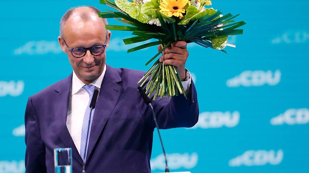 Friedrich Merz, CDU-Bundesvorsitzender, hält seinen Blumenstrauß nach der Wahl zum Bundesvorsitzenden beim CDU-Bundesparteitag hoch. Foto: Carsten Koall/dpa
