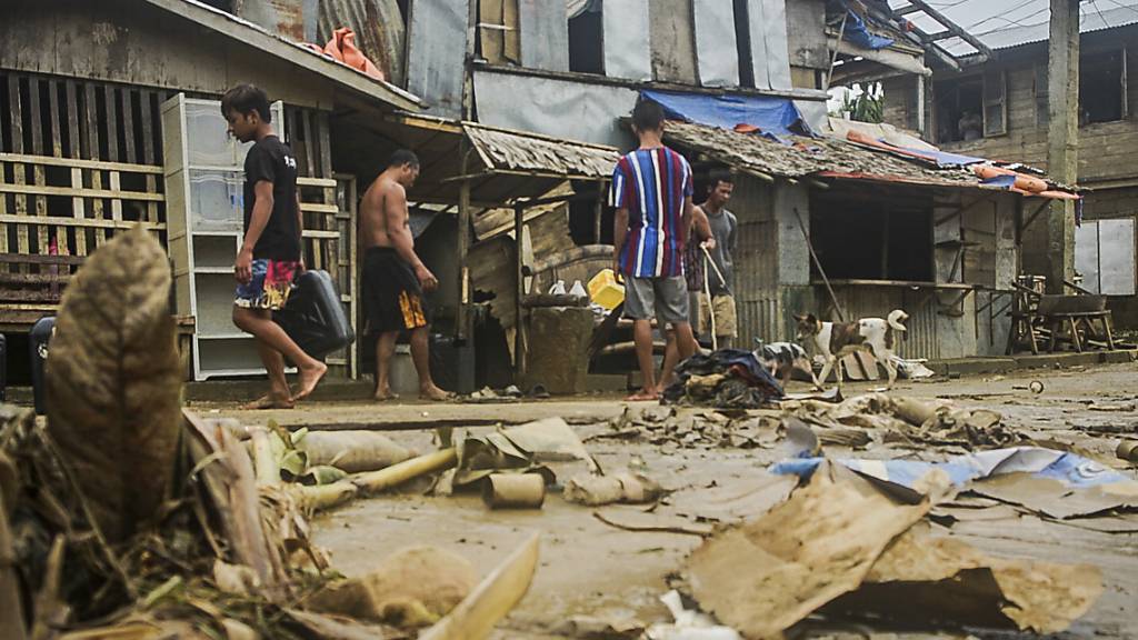Anwohner räumen Trümmer von den Überschwemmungen durch den Taifun «Surigae» auf. Foto: Uncredited/AP/dpa