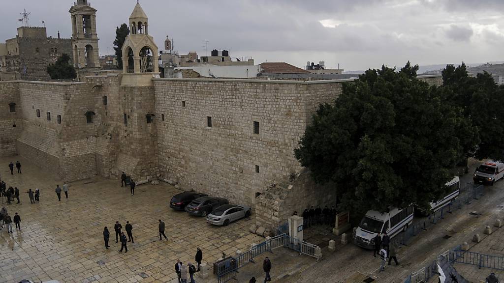 Menschen gehen am Heiligabend in der Stadt Bethlehem im Westjordanland an der Geburtskirche vorbei. Foto: Mahmoud Illean/AP/dpa