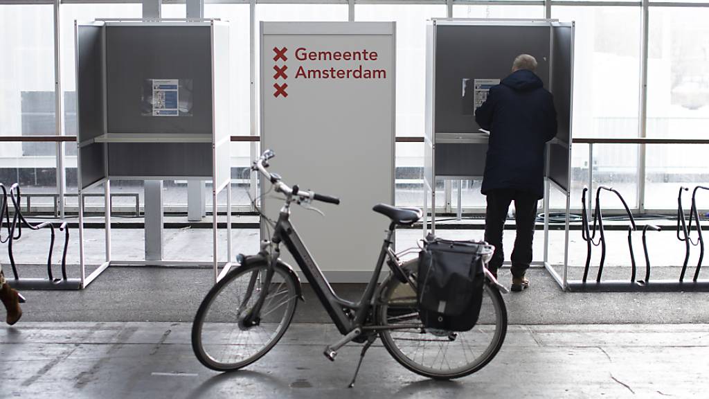 Ein Fahrrad steht vor Wahlkabinen, die neben Fahrradständern aufgebaut sind. Die Wahlen zum neuen niederländischen Parlament haben begonnen. Rund 13 Millionen Bürger sind aufgerufen, die 150 Abgeordneten der Zweiten Kammer zu wählen. Wegen der Corona-Pandemie wird die Parlamentswahl zum ersten Mal an insgesamt drei Tagen stattfinden. Foto: Peter Dejong/AP/dpa
