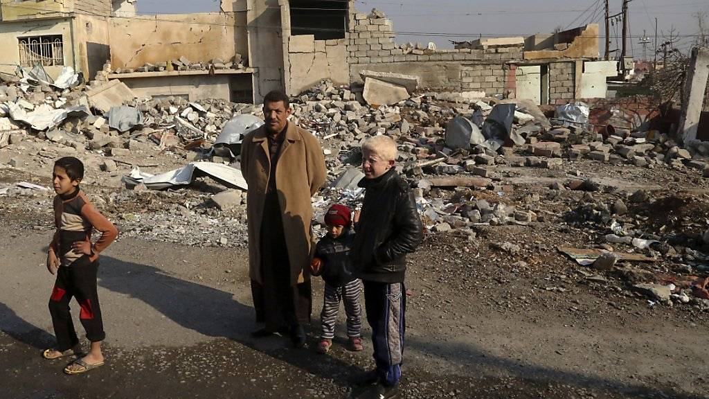 Eine Familie steht vor ihrem zerstörten Haus im Ostteil von Mossul.