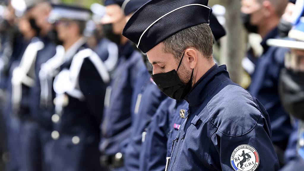 Ein Polizist hat seine Augen geschlossen und neigt seinen Kopf während einer Zeremonie zu Ehren des Polizisten Eric Masson. Masson wurde an einem Drogenumschlagplatz in Avignon getötet. Foto: Nicolas Tucat/POOL AFP/AP/dpa