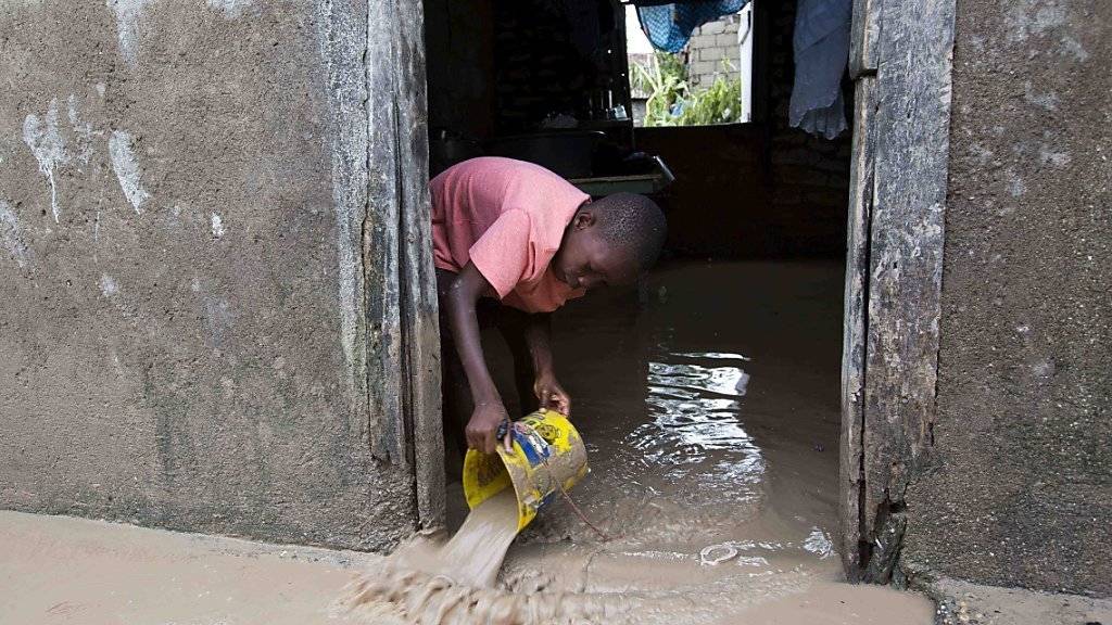 Das Haus in Les Cayes im Südwesten Haitis ist überschwemmt. Nun versucht der junge Bewohner, wenigstens einen Teil des Schlamms zu beseitigen.