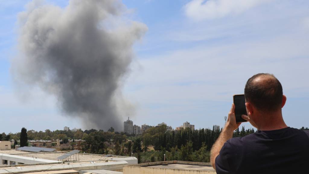 dpatopbilder - Ein Mann fotografiert mit seinem Mobiltelefon den Rauch, der nach einem israelischen Luftangriff in der südlichen Hafenstadt Tyros aufsteigt. Foto: Uncredited/AP/dpa