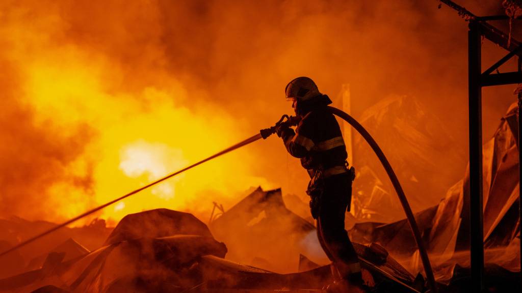 dpatopbilder - Feuerwehrleute löschten einen Brand, nachdem russische Raketen ein Lagerhaus getroffen hatten. Foto: Dan Bashakov/AP/dpa