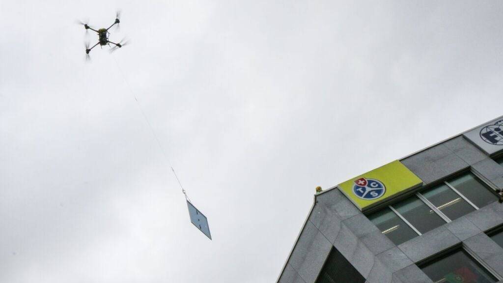 Eine Lastendrohne von TCS Drops fliegt ein Solarpanel auf das Dach des TCS-Hauptsitzes in Vernier GE.