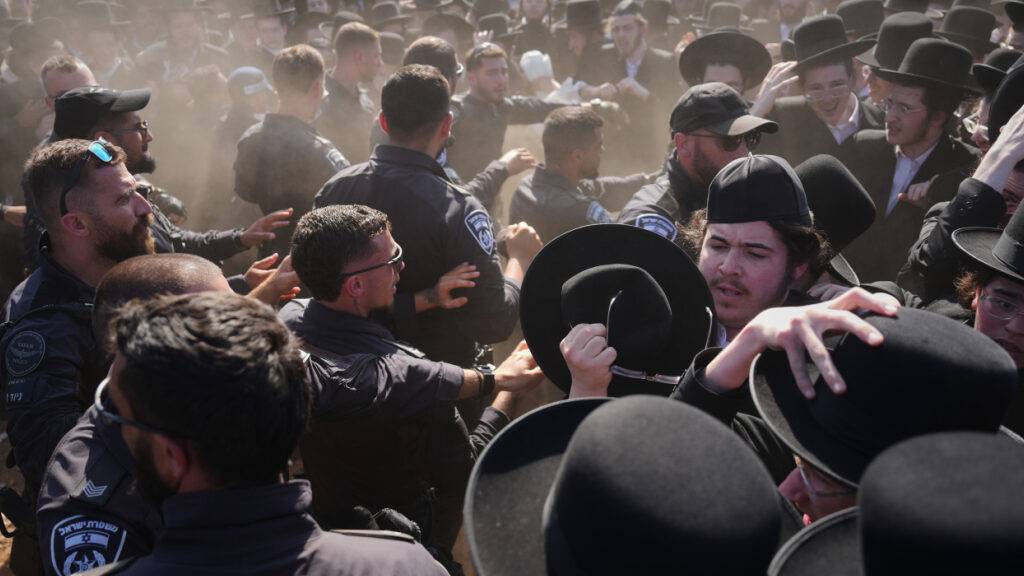 Ultraorthodoxe jüdische Männer geraten während einer Demonstration gegen die Wehrpflicht für alle vor einem Militärgefängnis in der Nähe von Kfar Yona, Israel, am Mittwoch mit der Polizei aneinader. Die Demonstranten und fordern die Freilassung inhaftierter Wehrdienstverweigerer. Foto: Ariel Schalit/AP/dpa