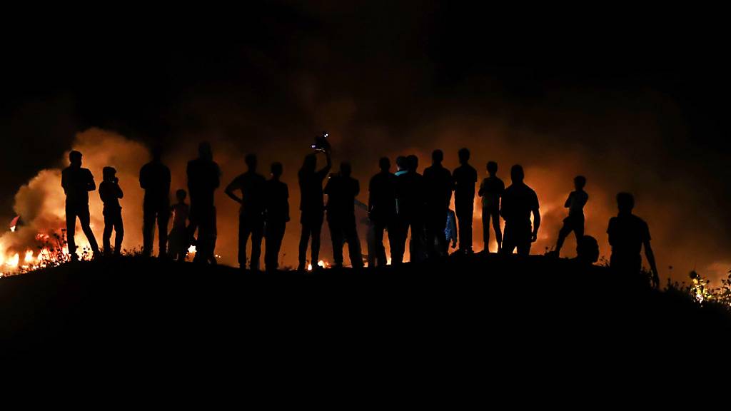 Palästinensische Demonstranten werfen ein brennendes Projektil in Richtung der israelischen Streitkräfte während einer Demonstration östlich von Gaza-Stadt, um gegen den Flaggenmarsch israelischer Nationalisten in Jerusalems Altstadt zu protestieren. Foto: Naaman Omar/APA Images via ZUMA Wire/dpa