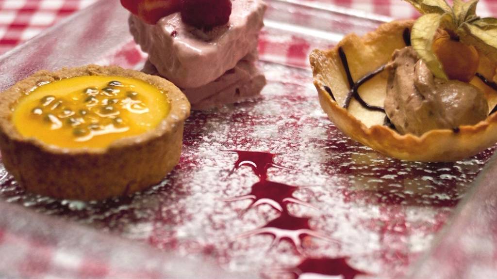 Desserttrilogie aus Tarte au fruit de passion, Tobleronemousse und Erdbeer-Himbeerrahmgefrorenes