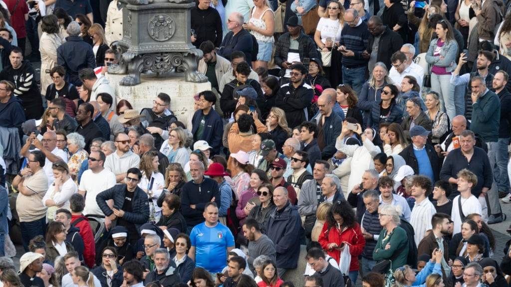 Menschen stehen nach Beginn des Konklave zur Wahl eines neuen Papstes auf dem Petersplatz. Foto: Marijan Murat/dpa