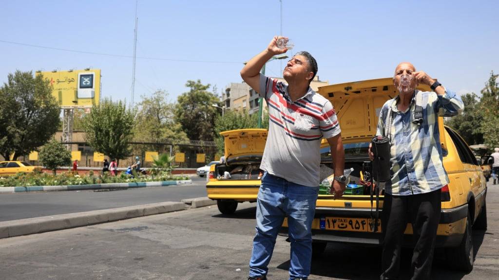 Zwei Taxifahrer erfrischen sich während einer Hitzewelle in der iranischen Hauptstadt. Die Millionenmetropole steht vor einer Wasserkrise. Foto: str/-/dpa