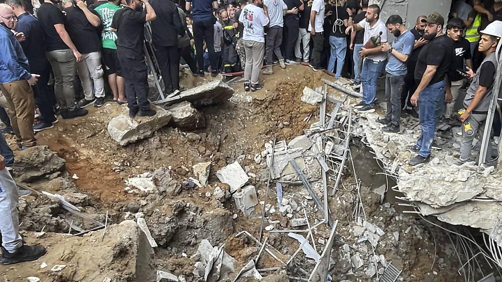 Menschen versammeln sich am Ort eines israelischen Raketeneinschlags in den südlichen Vororten von Beirut. Foto: Bilal Hussein/AP