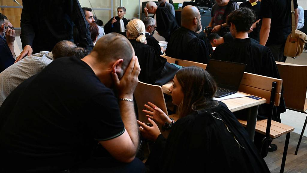 Mitangeklagte sprechen mit einer Anwältin (r) im Gerichtsgebäude während des Prozesses. Foto: Christophe Simon/AFP/dpa