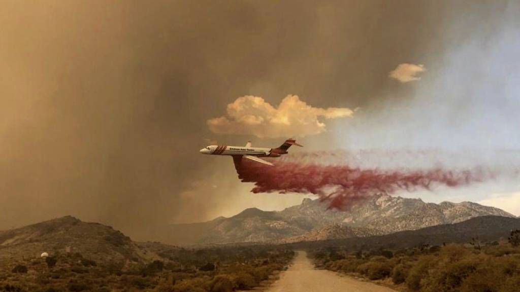 HANDOUT - Ein Löschflugzeug ist über dem Mojave National Preserve im Einsatz, einem Schutzgebiet im US-Bundesstaat Kalifornien. Foto: R. Almendinger/National Park Service Mojave National Preserve/AP/dpa - ACHTUNG: Nur zur redaktionellen Verwendung und nur mit vollständiger Nennung des vorstehenden Credits