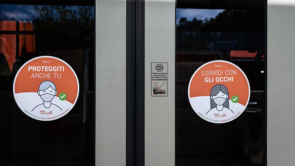 Hinweisschilder auf die Maskenpflicht an den Türen eines Lokalzugs der Lugano-Ponte-Tresa-Bahn FLP.
