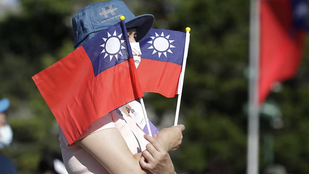 ARCHIV - Eine Frau macht ein Foto mit taiwanesischen Nationalflaggen. Foto: Chiang Ying-Ying/AP/dpa/Archiv