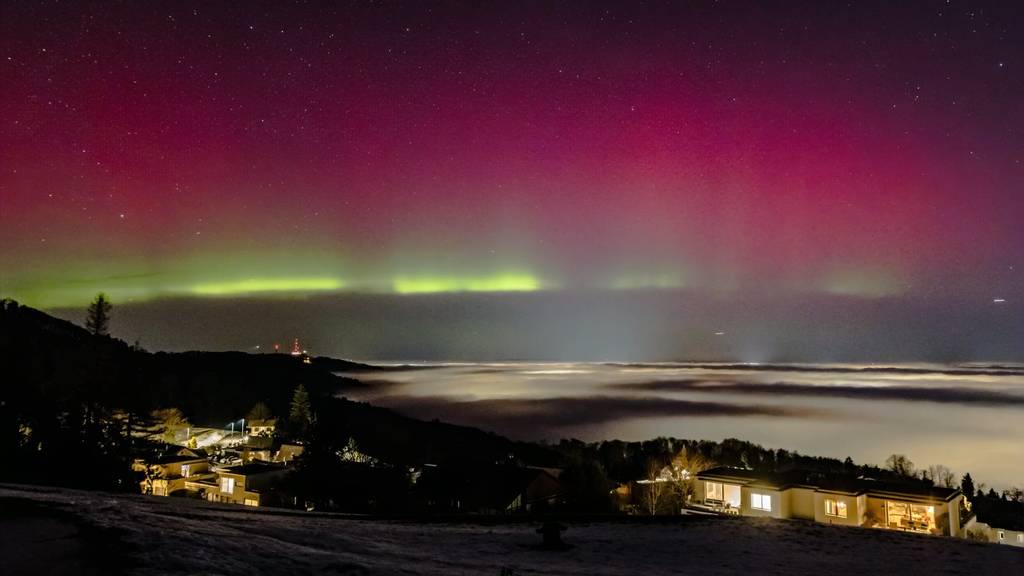 Nordlichter leuchten am Nachthimmel über dem Zürichsee