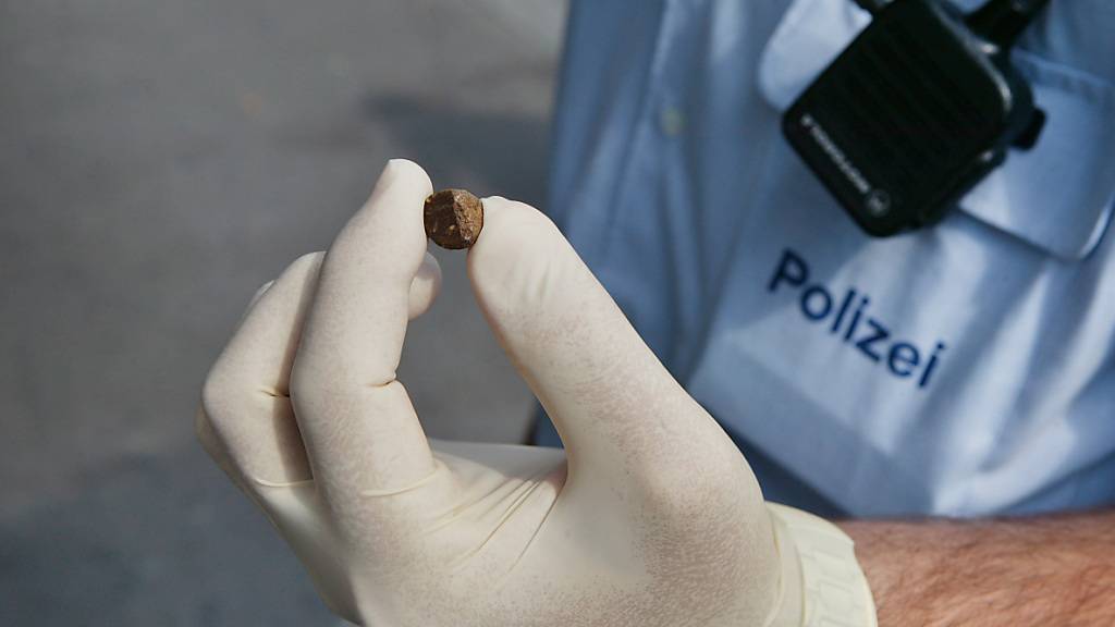 Ein Polizei-Mitarbeiter zeigt eine kleine Portion Haschisch. (Archivbild)
