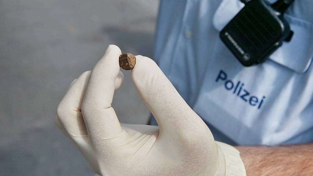 Ein Polizei-Mitarbeiter zeigt eine kleine Portion Haschisch. (Archivbild)