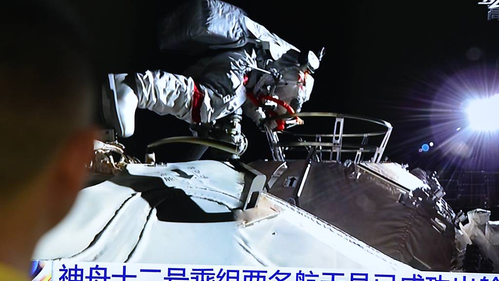 ARCHIV - Ein Mann verfolgt die Live-Übertragung über Astronauten des chinesischen Raumschiffs «Shenzhou 12», die in ihren Raumanzügen die Station verlassen 04.07.2021). Die drei Astronauten sind nach der Mission wieder auf der Erde gelandet. Foto: Sheldon cooper/SOPA Images via ZUMA Wire/dpa