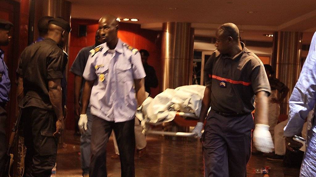 Sicherheitskräfte bergen die Leiche eines der 21 Opfer der Geiselnahme in Mali.