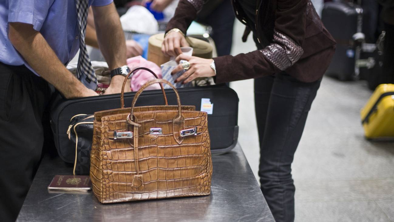 Zollbeamter durchsucht am Flughafen den Koffer einer Reisenden bei der Ankunft