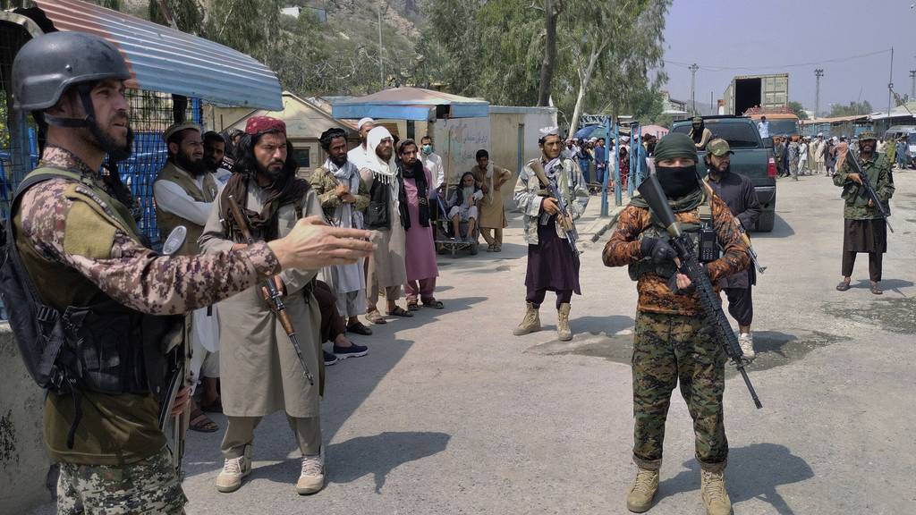 A Pakistani paramilitary soldier, left, and Taliban fighters stand guard on their respective sides, at a border crossing point between Pakistan and Afghanistan, in Torkham, in Khyber district, Pakistan, Sunday, Sept. 5, 2021. Pedestrian movement is limited at the Torkham border, with only legitimate document holders on both sides and trucks taking goods to Afghanistan passing through this border point.