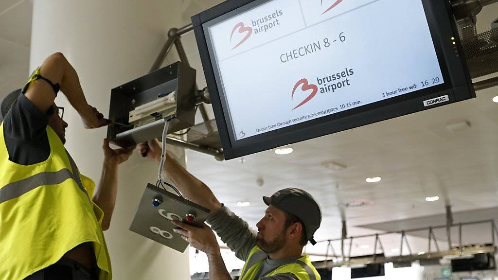 Arbeiter reparieren einen Bildschirm in der Abflughalle des Brüsseler Flughafens Zaventem. Ein Teil der Abflughalle soll am Sonntag wieder in Betrieb gehen.