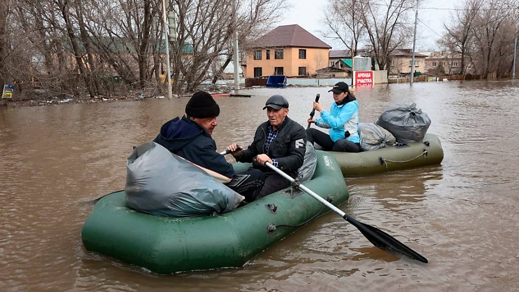 Anwohner paddeln in Schlauchbooten auf einer überfluteten Straße. Wegen Überschwemmungen wurden tausende Menschen in der Region Orenburg, die etwa 1.200 Kilometer südöstlich von Moskau liegt, evakuiert. Foto: v.v.smolnikov/AP/dpa