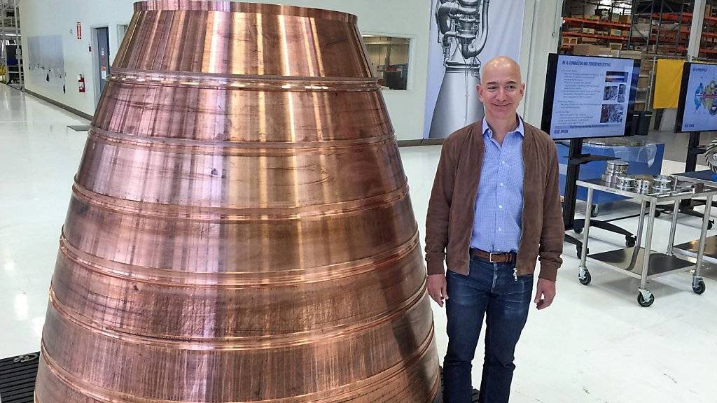 Amazon-Gründer Jeff Bezos neben einem Antriebsteil für eine Rakete mit der künftig Passagiere ins Weltall fliegen sollen.