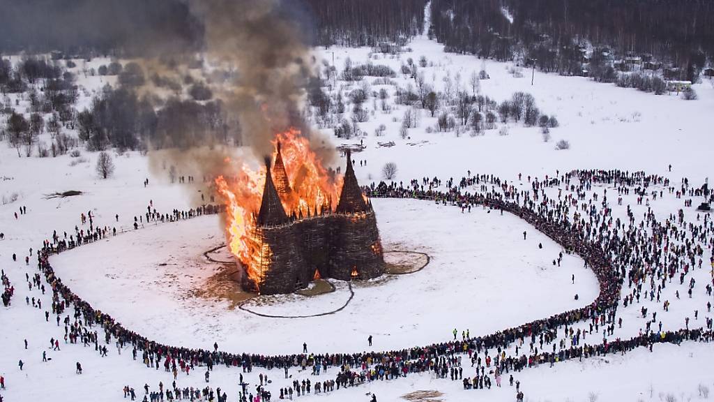 dpatopbilder - Menschen beobachten die Verbrennung einer schlossförmigen Holzkonstruktion als Teil der Feierlichkeiten zum Masleniza-Fest im Nikola-Lenivets-Kunstpark. Foto: Dmitry Serebryakov/AP/dpa