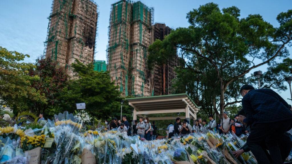 Trauernde legen nach dem tödlichen Brand Blumen an einer behelfsmäßigen Gedenkstätte in der Nähe des Wohnkomplexes Wang Fuk Court in Tai Po nieder. Foto: Vernon Yuen/Nexpher via ZUMA Press Wire/dpa