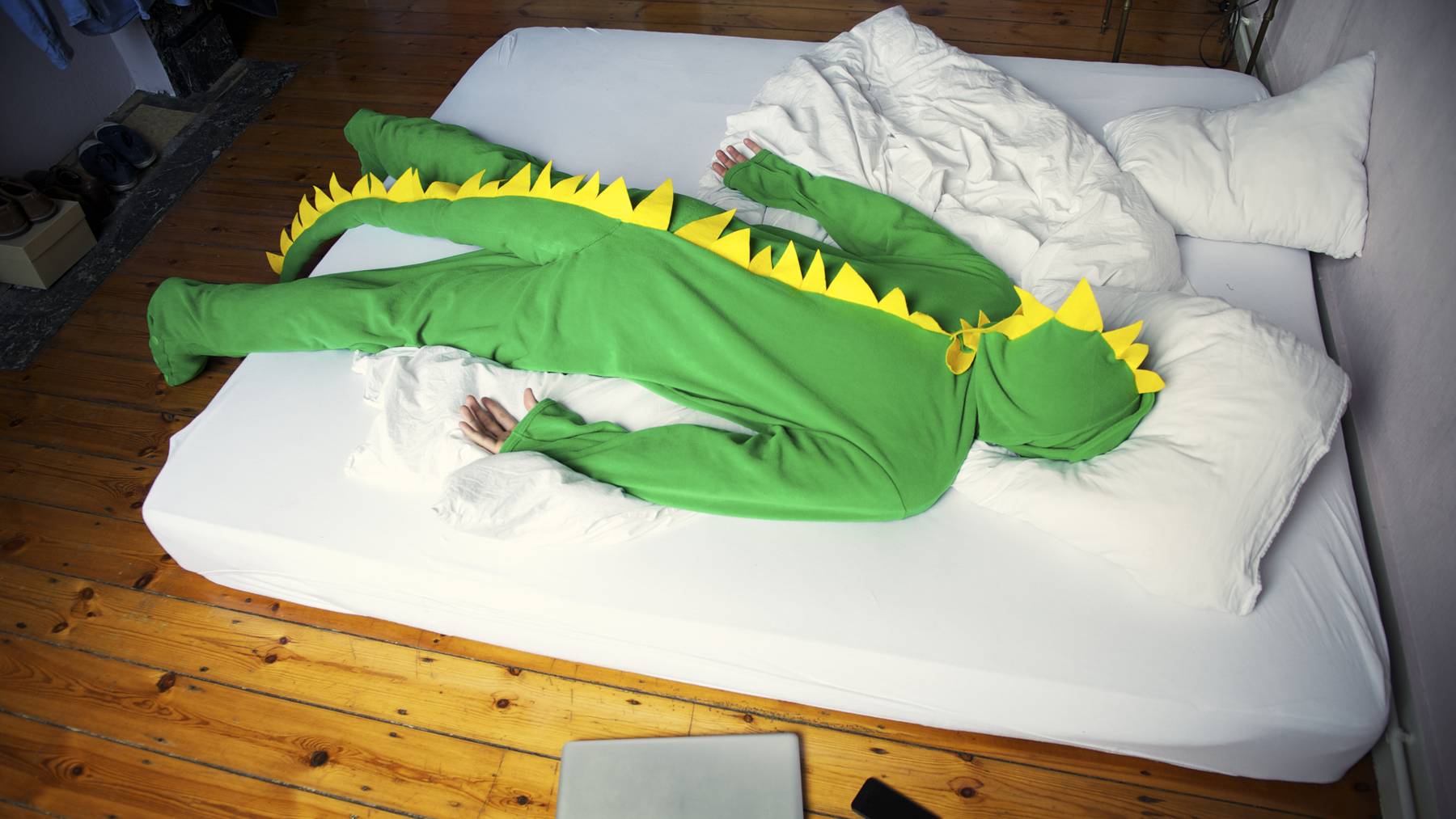 Eine Person in einem Fasnachtskostüm liegt auf einem weissen Bett.