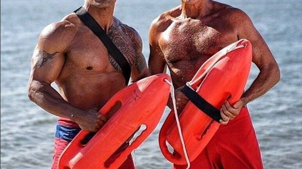 David Hasselhoff und Dwayne Johnson steigen als Rettungsschwimmer ins Meer.
