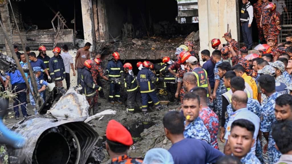 Feuerwehrleute suchen nach den Überlebenden eines Trainingsflugzeugs der Bangladesh Air Force, das kurz nach dem Start auf ein Schulgelände gestürzt ist. Foto: Mahmud Hossain Opu/AP/dpa