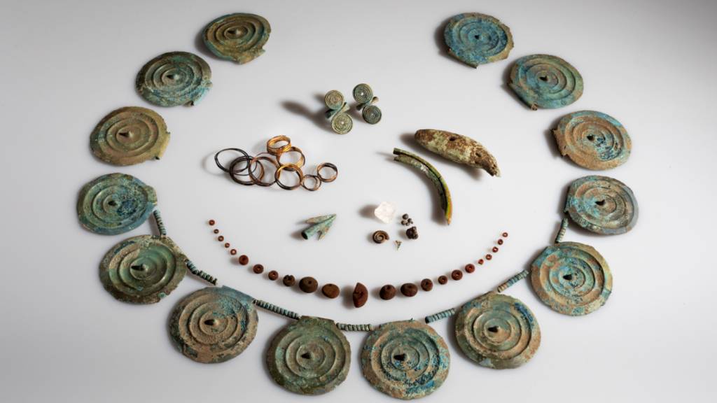 Der Fund der Archäologen umfasst ein Collier mit Stachelscheiben, eine Bernsteinkette, Fingerringe, Goldspiralen und einen Bärenzahn oder Ammoniten.