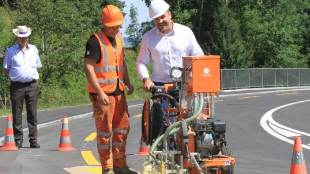 Baudirektor Florian Weber (FDP) bringt zur Eröffnung der sanierten Strasse eine Bodenmarkierung an.