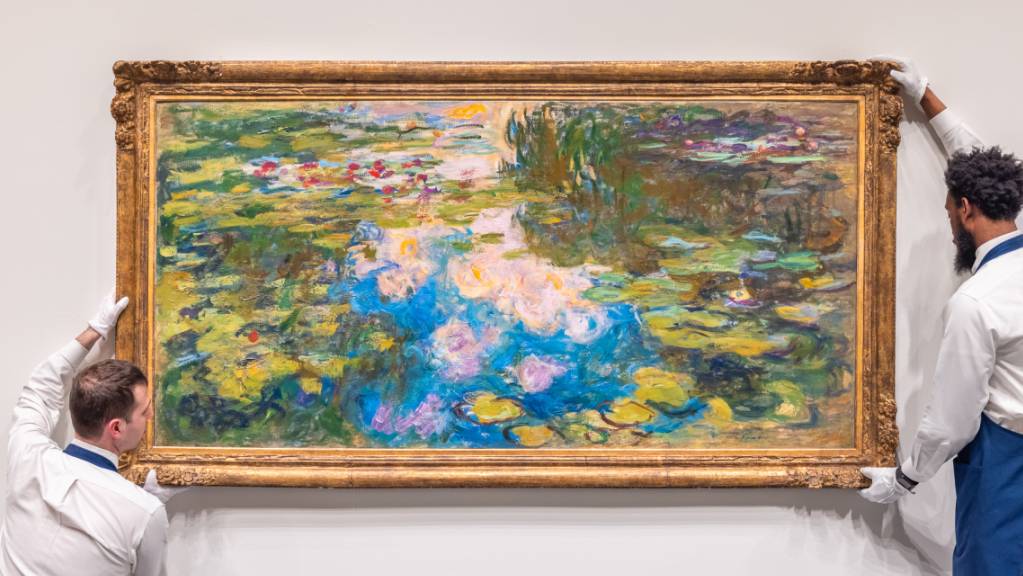Mitarbeiter des Auktionshauses Sotheby's hängen ein Seerosen-Werk des französischen Malers Claude Monet (1840-1926) an die Wand.