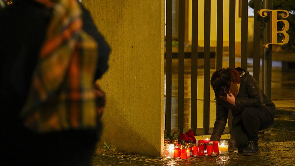 Eine Person entzündet Kerzen vor dem Gebäude der Philosophischen Fakultät der Karls-Universität in der Prager Innenstadt. Foto: Petr David Josek/AP/dpa