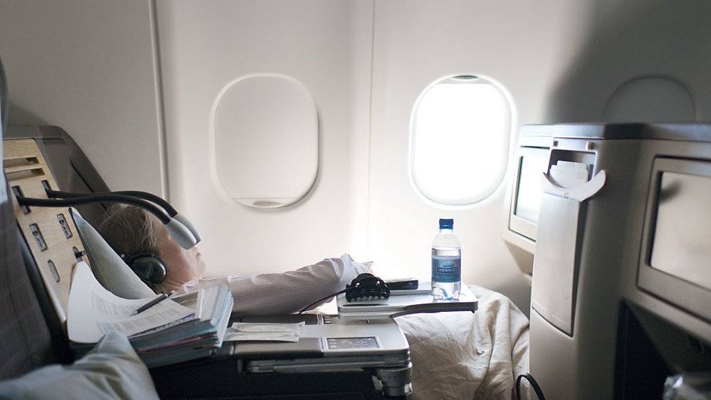 Eine schlafende Flugpassagierin in der Business Class. Wenn sich ihr Flug verspätet, kann ihr Arbeitgeber Schadenersatz von der Airline fordern. (Symbolbild)