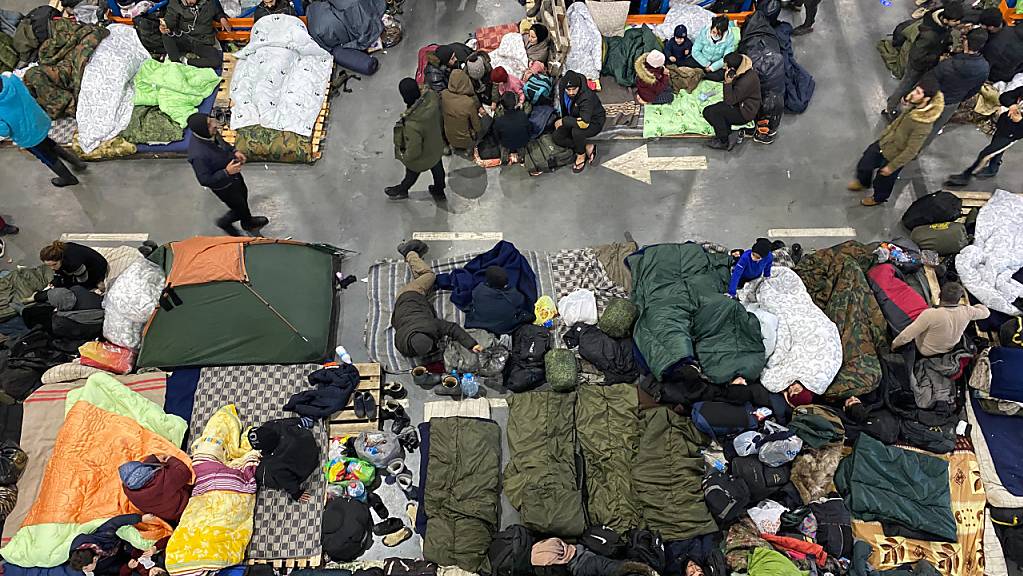 Menschen sind in der Notunterkunft in der Lagerhalle eines Logistikzentrums nahe der Grenze zu Polen untergebracht. Foto: Ulf Mauder/dpa